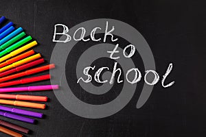 Back to school background with colorful felt tip pens and title Back to school written by white chalk on the school