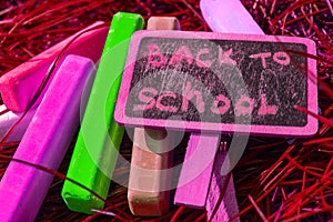 Back to school background with colorful neon colored crayons, on purple glowing background. Flat position, top view, copy space.