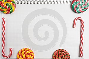 back to school background. colorful sweet candys on blank notepad with spiral. striped Candy Canes and spiral lollipops on paper