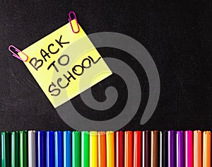 Back to school background with a lot of colorful felt-tip pens and colorful pencils, titles Back to school on the yellow