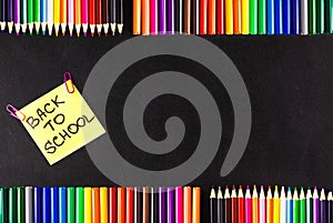 Back to school background with a lot of colorful felt-tip pens and colorful pencils, titles Back to school on the yellow