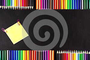 Back to school background with a lot of colorful felt-tip pens and colorful pencils, the yellow piece of paper o