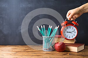 Back to school background with pencils, apple, books and alarm clock over chalkboard