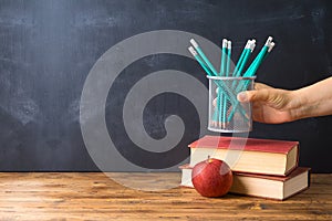 Back to school background with pencils, apple, books and alarm clock over chalkboard