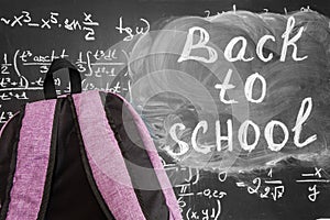 Back to school background with purple school bag and the title `Back to school` and math formulas written by white chalk