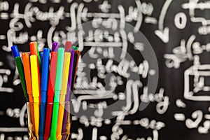 Back to school background with school bus and school are written by colorful chalks on the black school chalkboard