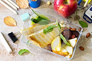 Back to school background. School lunch box, apple and school supplies on a light stone or slate background