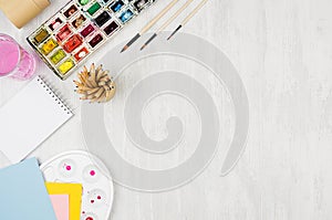 Back to school background - stationery for creativity - watercolor paints, palette, brushes, colored pencils on white wood table,
