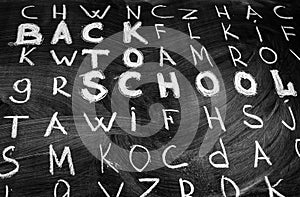 Back to school background with title Back to school among other letters of English alphabet written by white chalk on