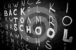 Back to school background with title `Back to school` among other letters of English alphabet written by white chalk