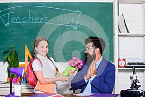 Back to school. Best wishes. Girl adorable pupil with backpack giving bouquet flowers teacher. Knowledge day