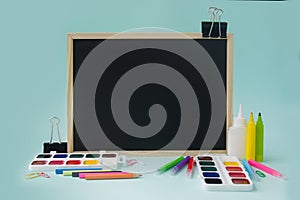 Back to school, a blackboard with stationery on a blue background. Copyspace