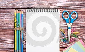 Back to school. Blank notepad and school stationery on a wooden background. Flatlay composition. Mockup. Top view. Copy space