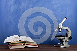 Back to school - books and microscope on the desk, Education concept. Blackboard background
