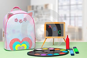 Back to school. Colorful school equipment, a bright school backpack and a blackboard with ABC letters on green table over an