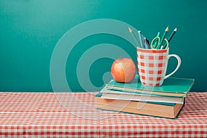 Back to school concept with books, pencils and apple on tablecloth