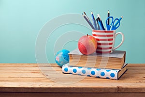 Back to school concept with books, pencils in cup, apple, and globe