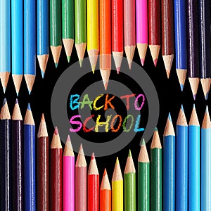 Back to school concept. Colorful pencils arranged as heart on black background.