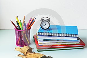 Back to school concept. Colorful pencils, books and alarm clock