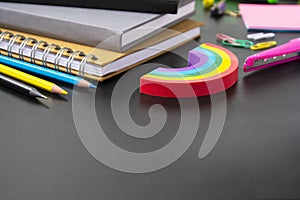 Back to school concept. Colorful pencils, rainbow eraser, notebook, sticky notes and office supplies on black background