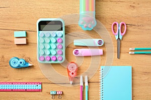 Back to school concept. Creative layout with calculator, proofreader, markers, scissors, pencils, notepad, eraser, ruler on wooden