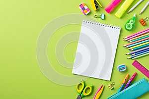 Back to school concept. Empty notepad with school stationery on green background