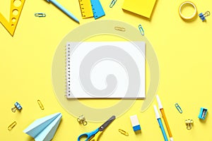 Back to school concept. Flat lay blank paper notepad with school stationery on yellow table. Top view