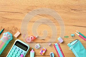 Back to school concept. Flat lay composition with school supplies in pink and turquoise colors on wooden desk. Top view calculator