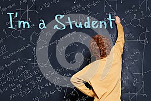 Back to school concept. Happy child student writing on blackboard background