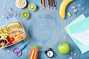 Back to school concept. Healthy lunch box and colorful stationery on blue table top view.