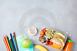 Back to school concept. Healthy lunch box and colorful stationery on gray stone table top view.