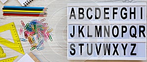 Back to school concept. Letters from A to Z. English alphabet on modern board and accessories for study over white wooden surface