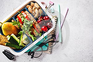 Back to school concept.  Lunch box with sandwich, fruit, snacks, notebook, pencils and school items, top view