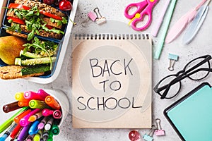 Back to school concept.  Lunch box with sandwich, fruit, snacks, notebook, pencils and school items, top view