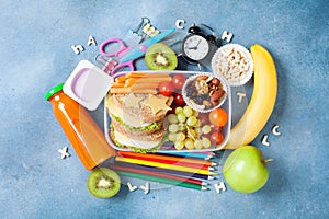 Back to school concept. Nutritional lunch box and colorful stationery on blue table top view.