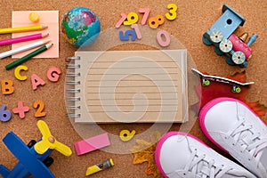 Back to school. Concept with pencils, letters, numbers and sneakers on a cork background. Opened notepad and globe. View from