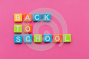 Back to school concept. Phrase `Back to School` from alphabet magnets on pink background