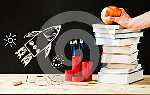 back to school concept pile of books against chalkboard