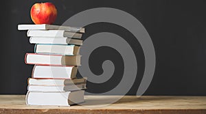 back to school concept pile of books against chalkboard