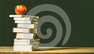 back to school concept pile of books against chalkboard