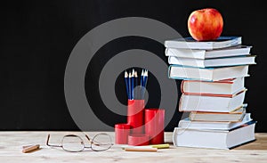 back to school concept pile of books against chalkboard