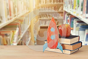 Back to school concept. rocket and books in front of blurry Library background.