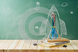 Back to school concept with rocket sketch, pencils and notebook on wooden table background