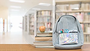 Back to school concept with school books, textbooks, backpack and stationery supplies on classroom desk with library or class