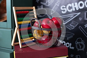 Back to school concept. School supplies, abacus, basket red apples on stack of books on background of chalkboard. Teachers day. Bl