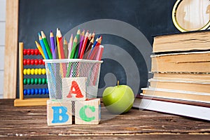 Back to school concept. School supplies, apple and a stack of books on the background of the blackboard