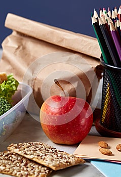 Back to School concept, school supplies, biscuits and lunchbox on white desk, selective focus, close-up.