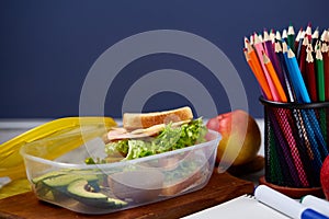 Back to School concept, school supplies, biscuits, packed lunch and lunchbox over white chalkboard, selective focus.