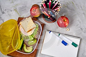 Back to School concept, school supplies, biscuits, packed lunch and lunchbox over white chalkboard, selective focus.