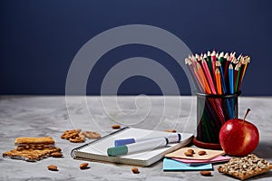 Back to School concept, school supplies, biscuits, packed lunch and lunchbox over white chalkboard, selective focus.